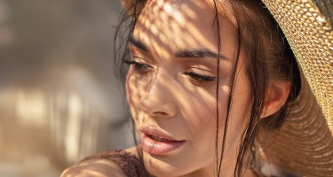 Portrait of beautiful young woman wearing summer hat . Closeup face of attractive girl posing in sunny vacation day.