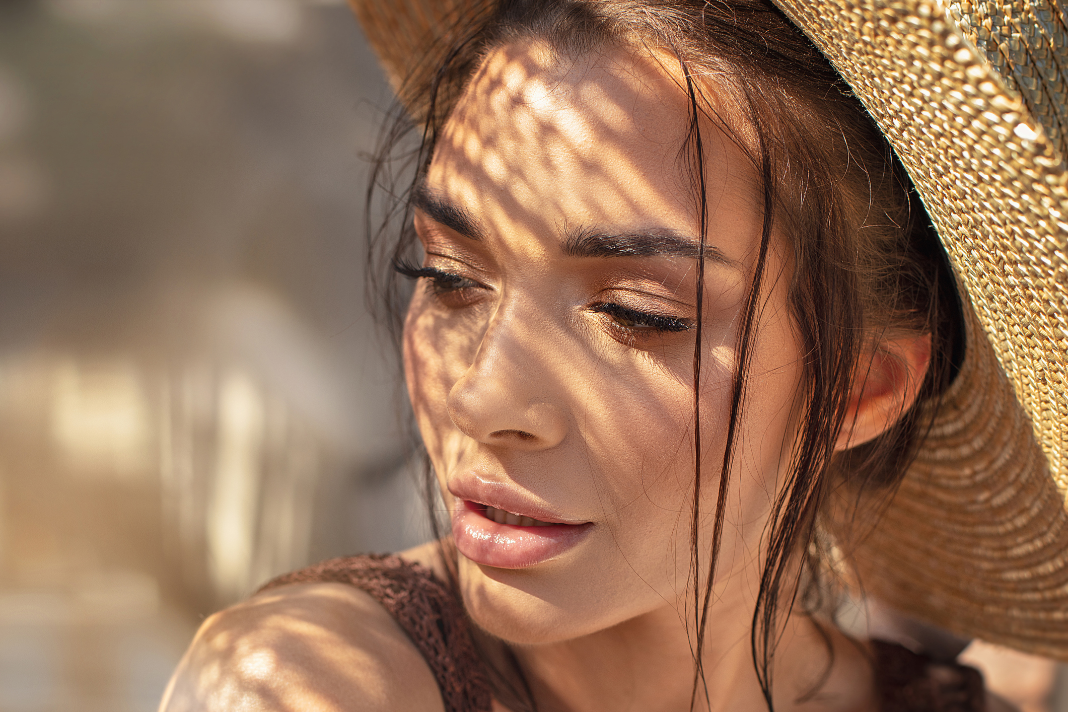 Portrait of beautiful young woman wearing summer hat . Closeup face of attractive girl posing in sunny vacation day.